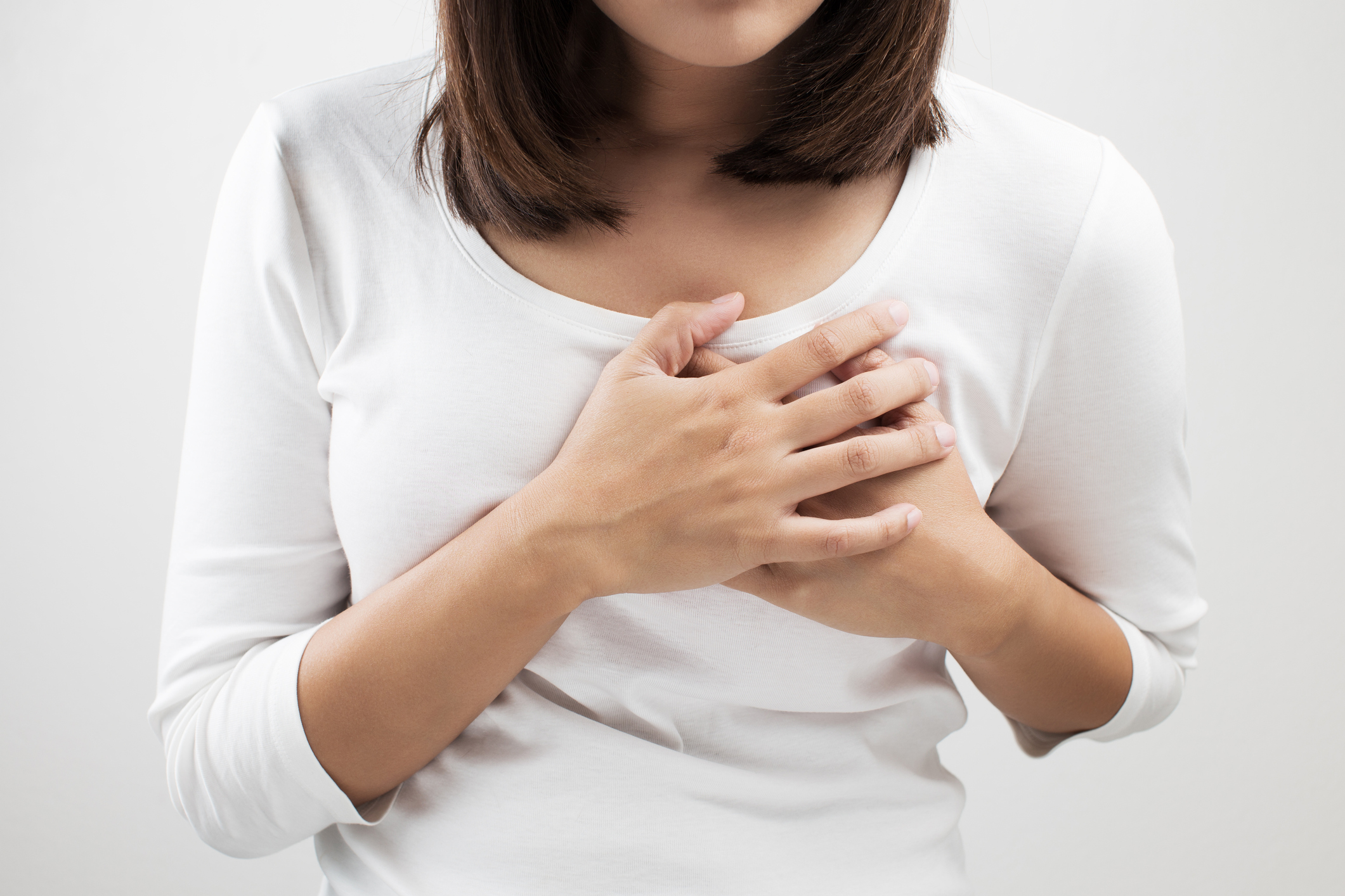 An image of a woman with acid reflux holding her chest in pain. 