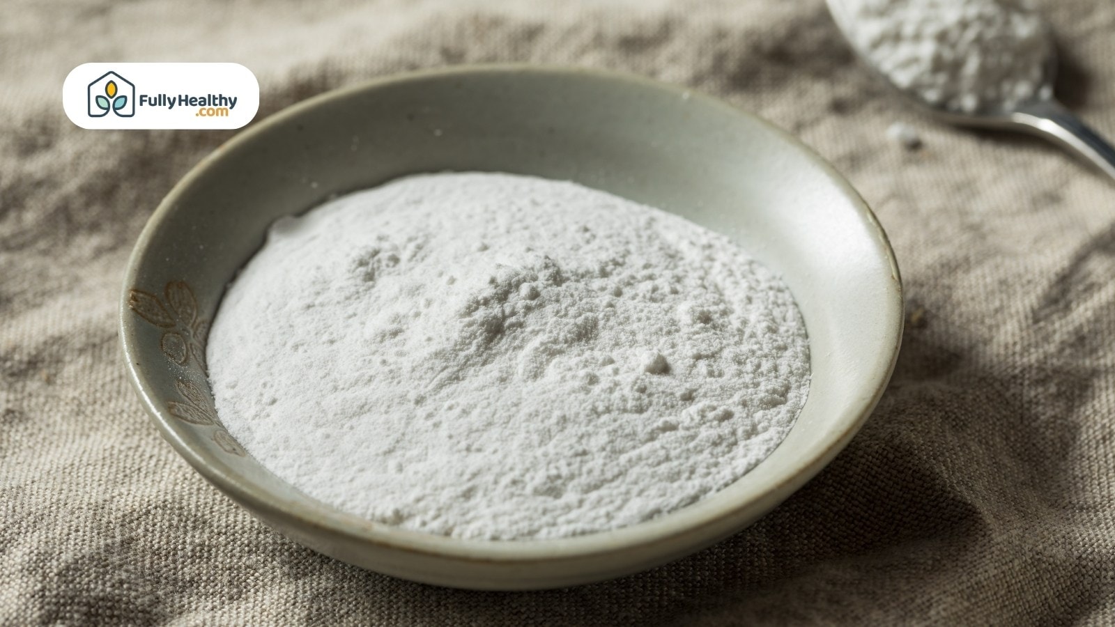 Cornstarch powder in ceramic bowl with spoon on burlap cloth