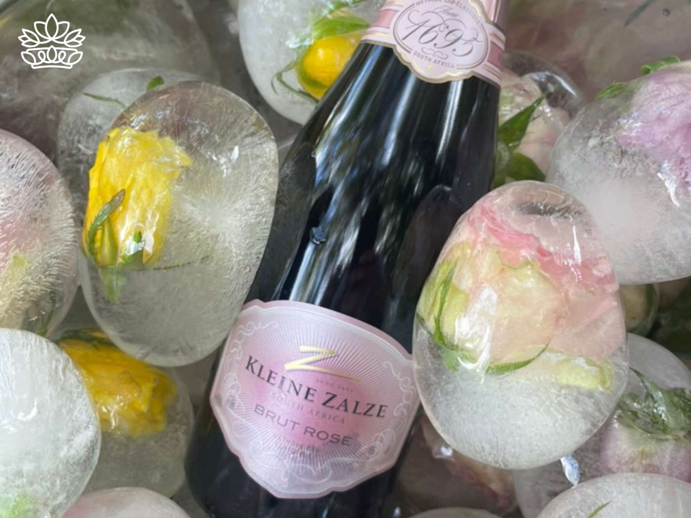 Bottle of Kleine Zalze Brut Rosé wine chilled among floral ice spheres, adding a touch of pink elegance to a traditional Easter basket, from the Easter Collection by Fabulous Flowers and Gifts.