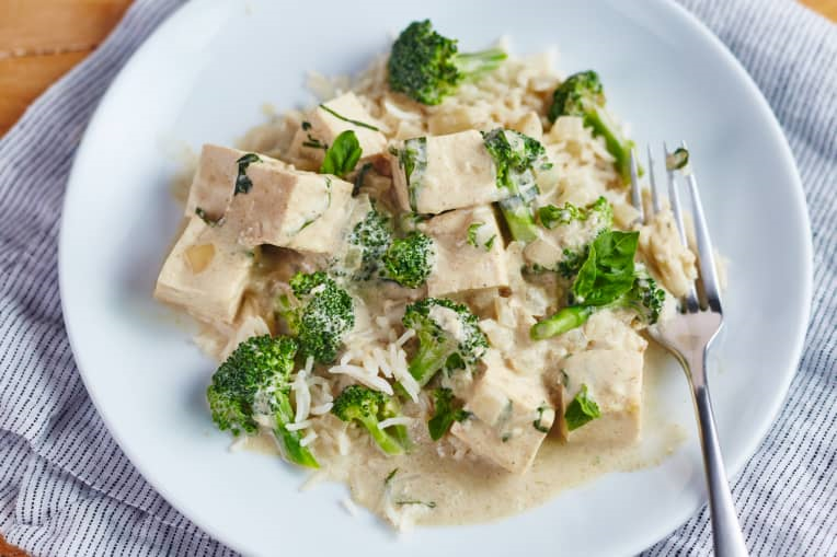 tofu and broccoli green curry on white plate with fork
