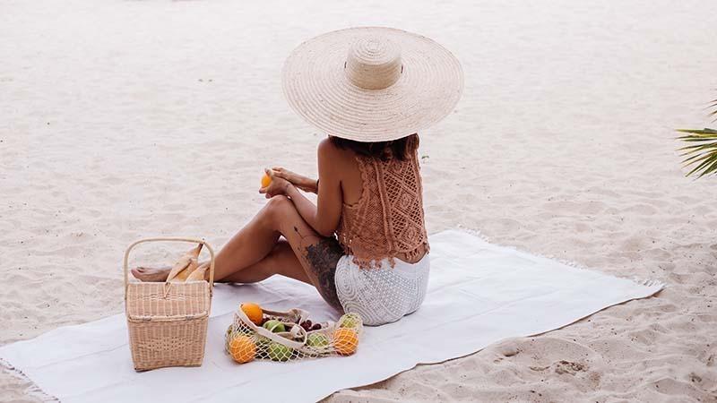 A woman sitting on a white beach towel