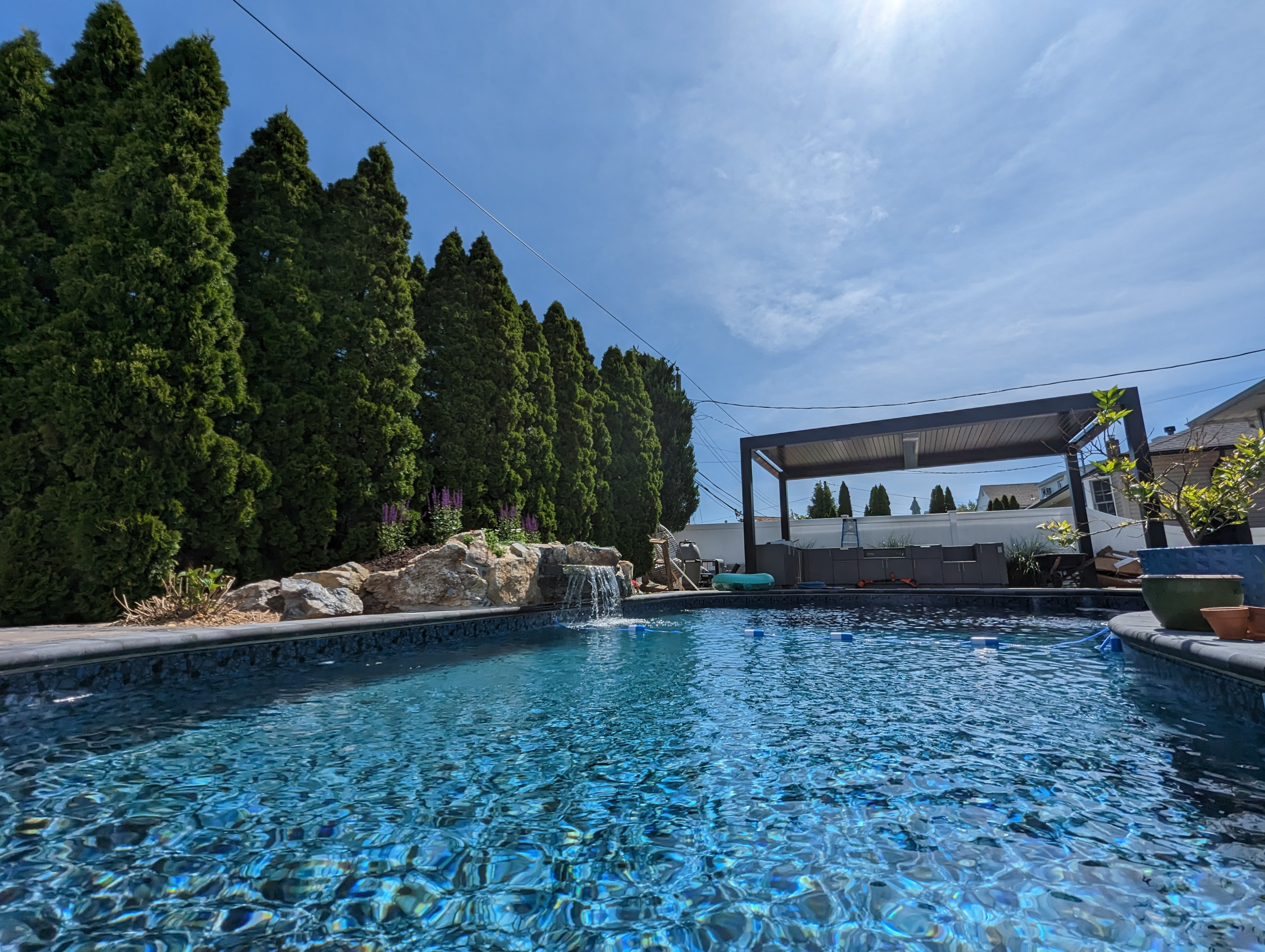 A poolside pergola with white pergola and potted plants, creating a perfect al fresco dining area