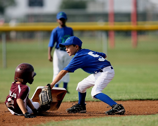 Little League players sliding into base with a possible tag out.