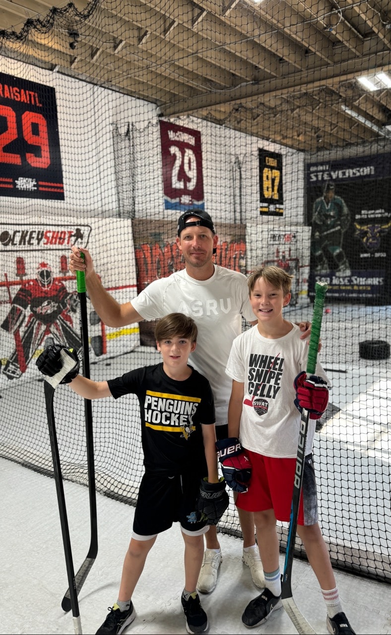 Coach Grant teaching teaching hockey shots to his students 