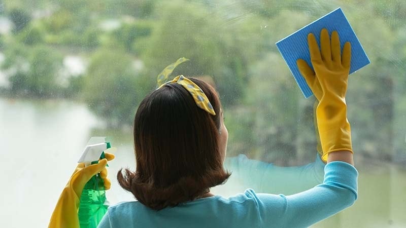 A woman is cleaning a hotel window with a microfiber cloth