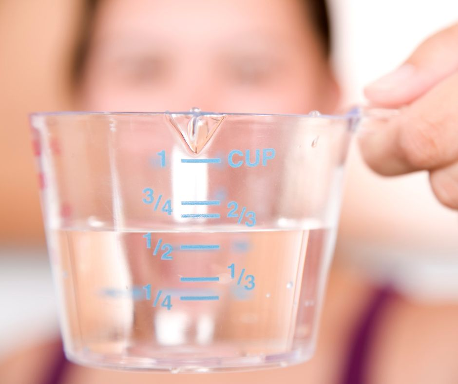 person looking at a liquid measuring cup of water