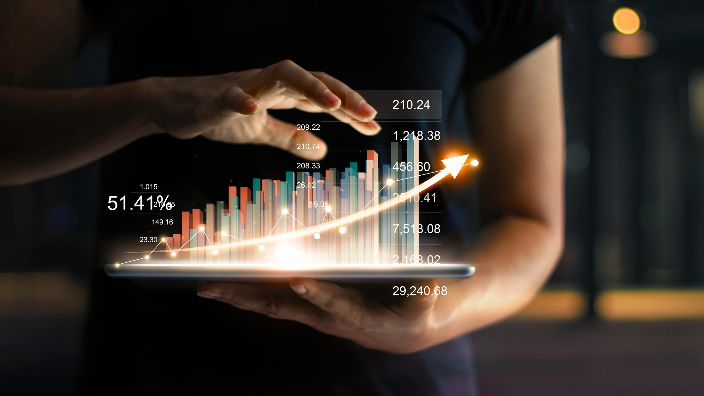 Person using a tablet with a holographic chart displaying upward growth and financial metrics, representing business growth and analytics.