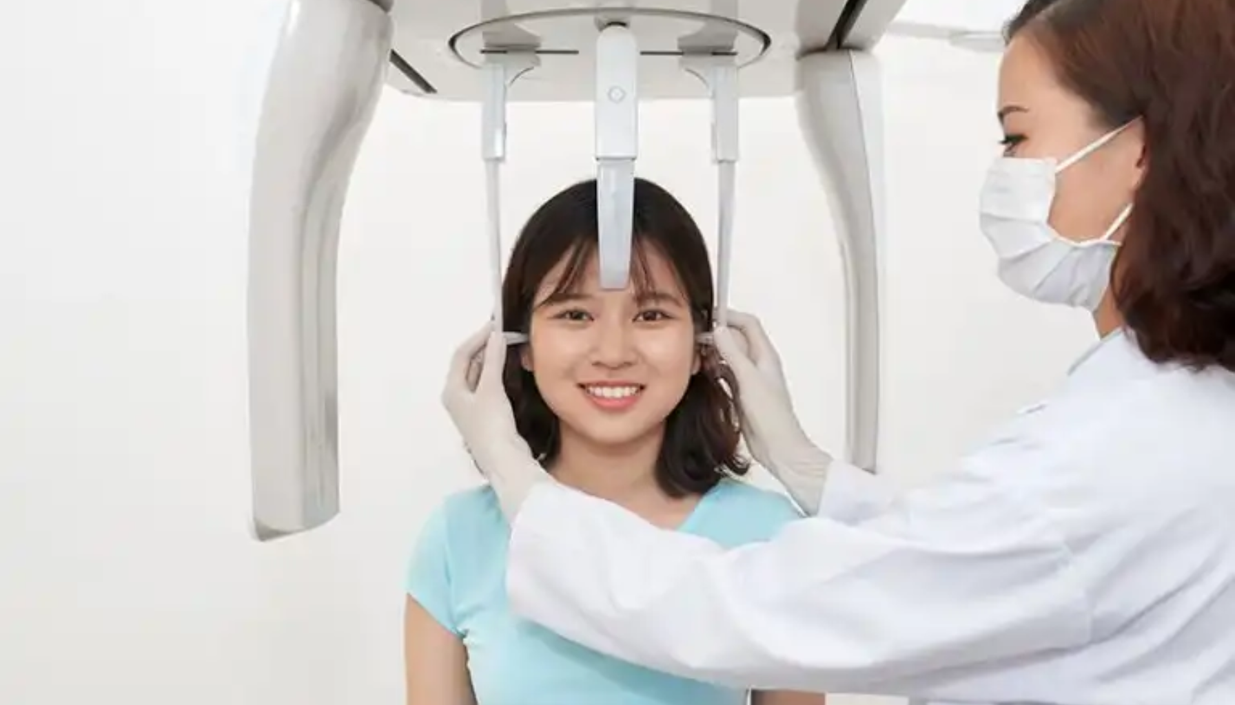 Tannlege posisjonerer pasient i panoramarøntgenmaskin for tann- og kjeveundersøkelse.