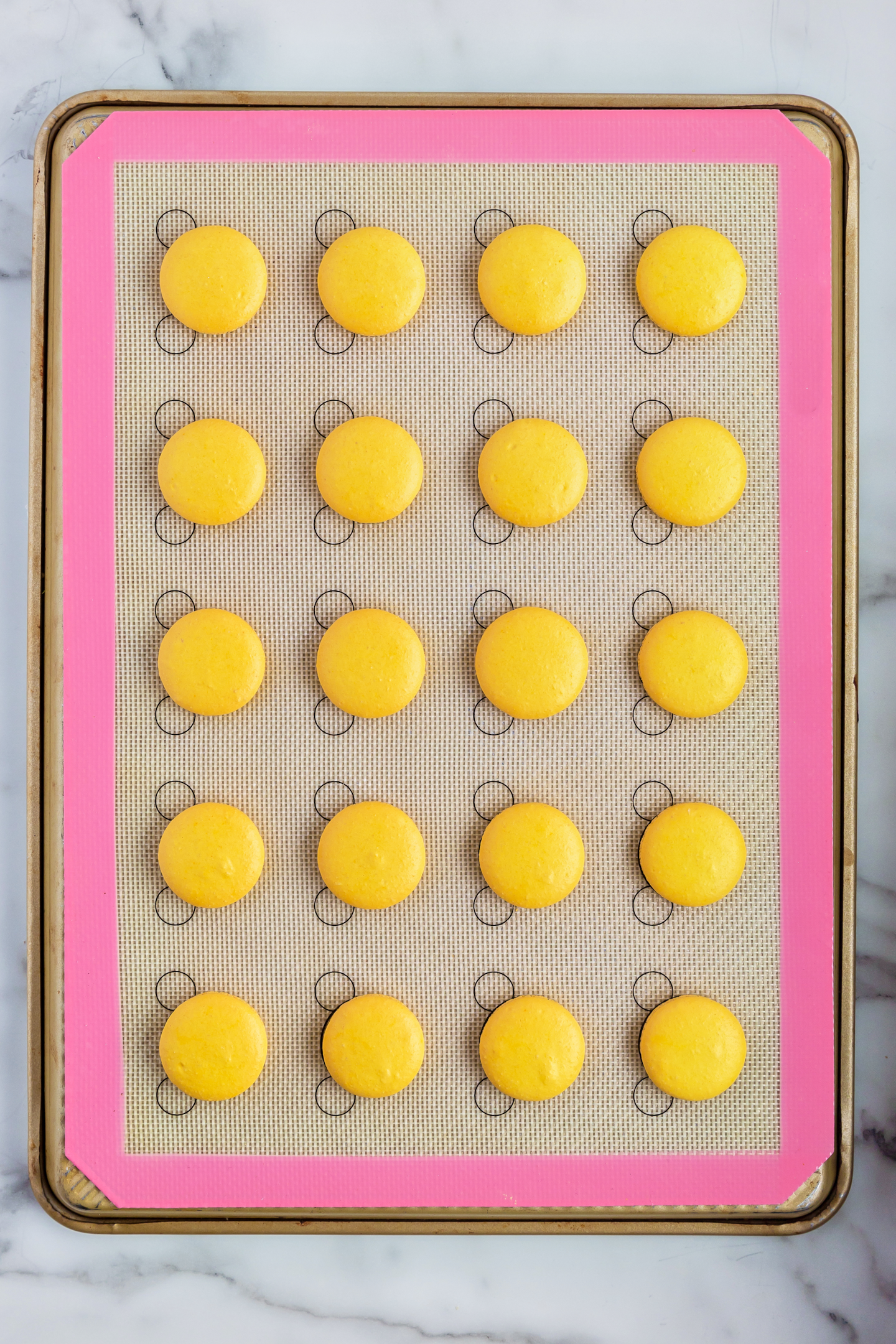 baked lemon macaron shells on silicone baking mat
