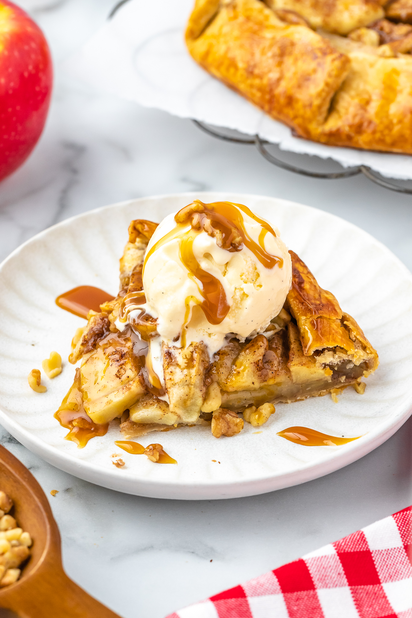 slice of apple crostata on a plate topped with ice cream and caramel sauce