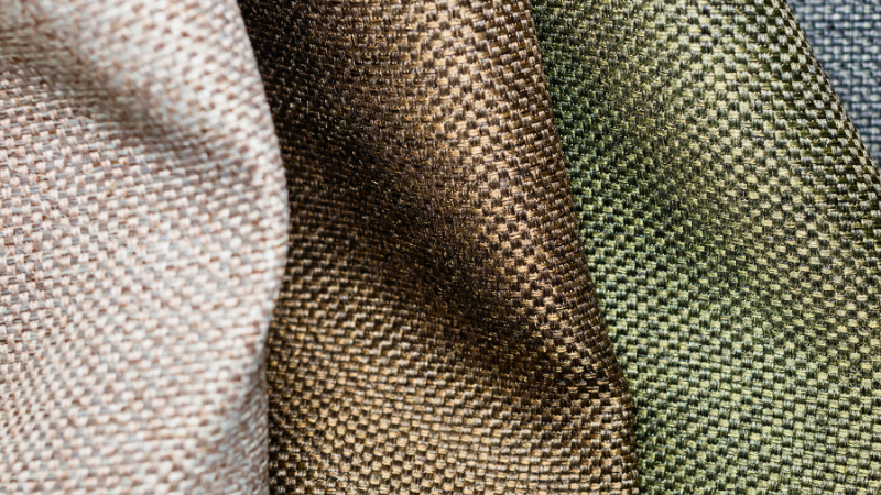 Close-up shot of textured polyester fabric in shades of beige, brown, green, and blue.