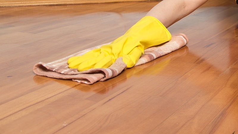 Women with yellow gloves cleaning floor with microfiber towel