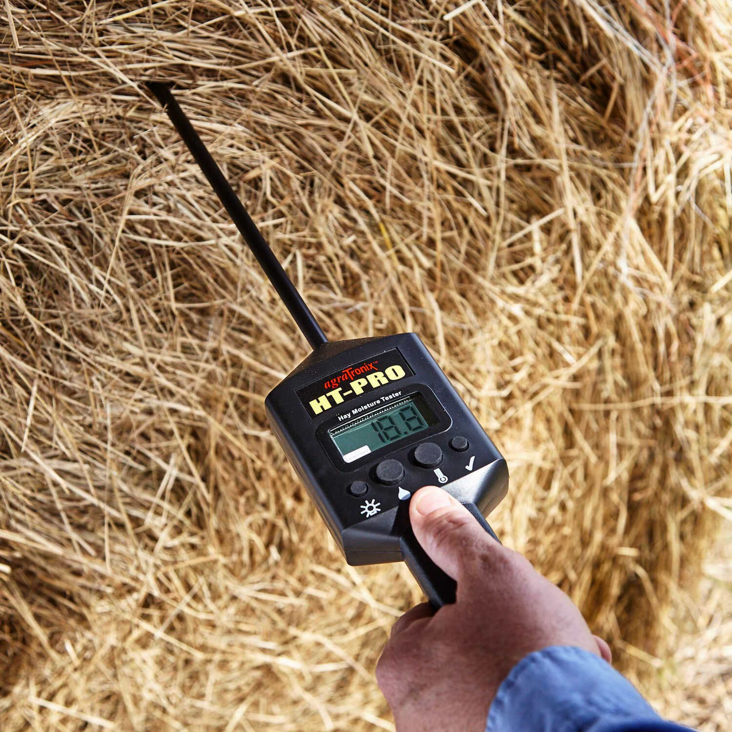 A portable hay moisture tester with a display showing the moisture content of the hay
