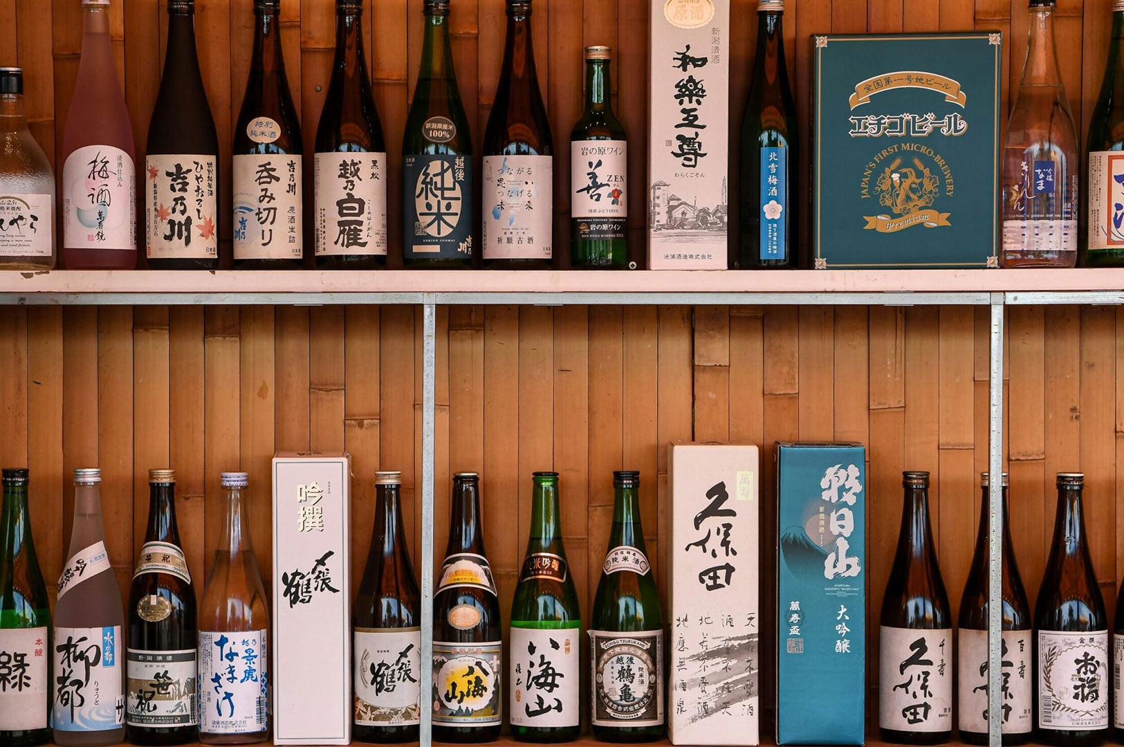 Assorted Japanese sake bottles displayed on shelves in an izakaya.