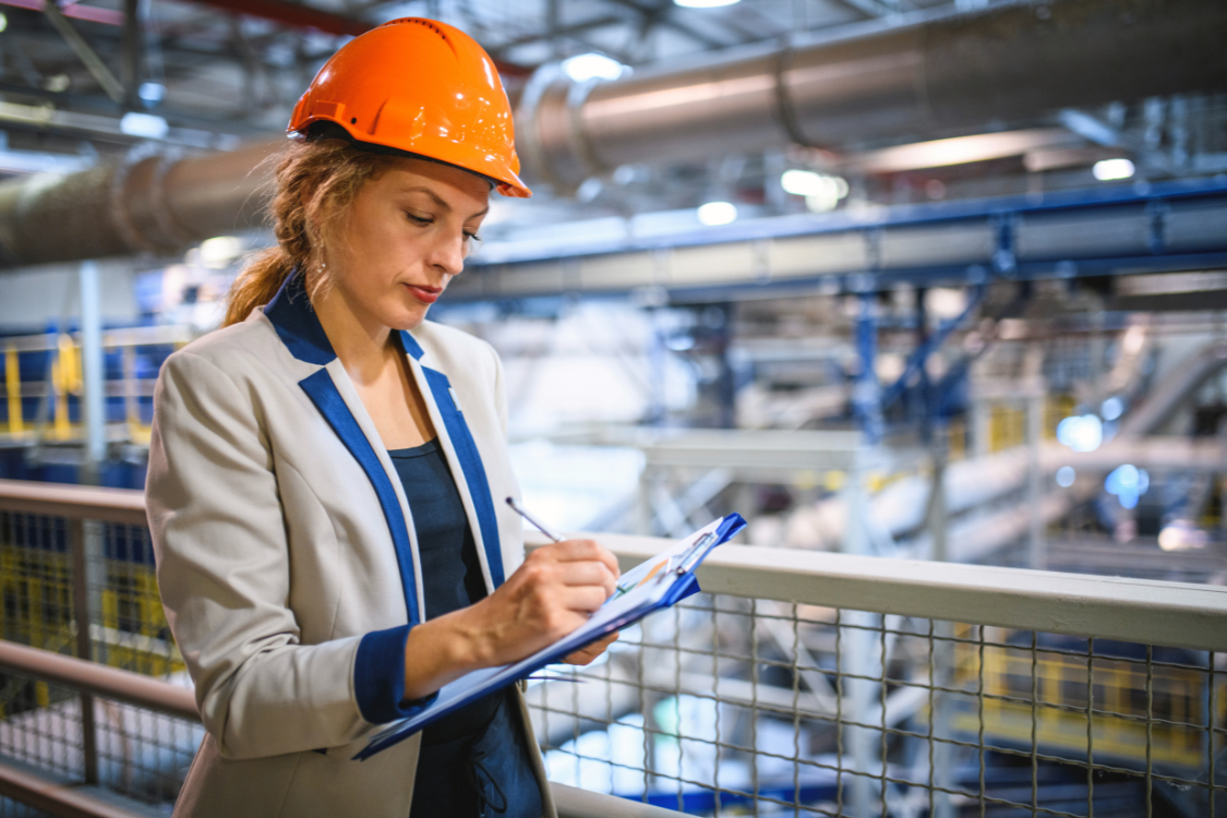 Facility inspector in a hard hat taking notes during an in-person supplement manufacturer visit