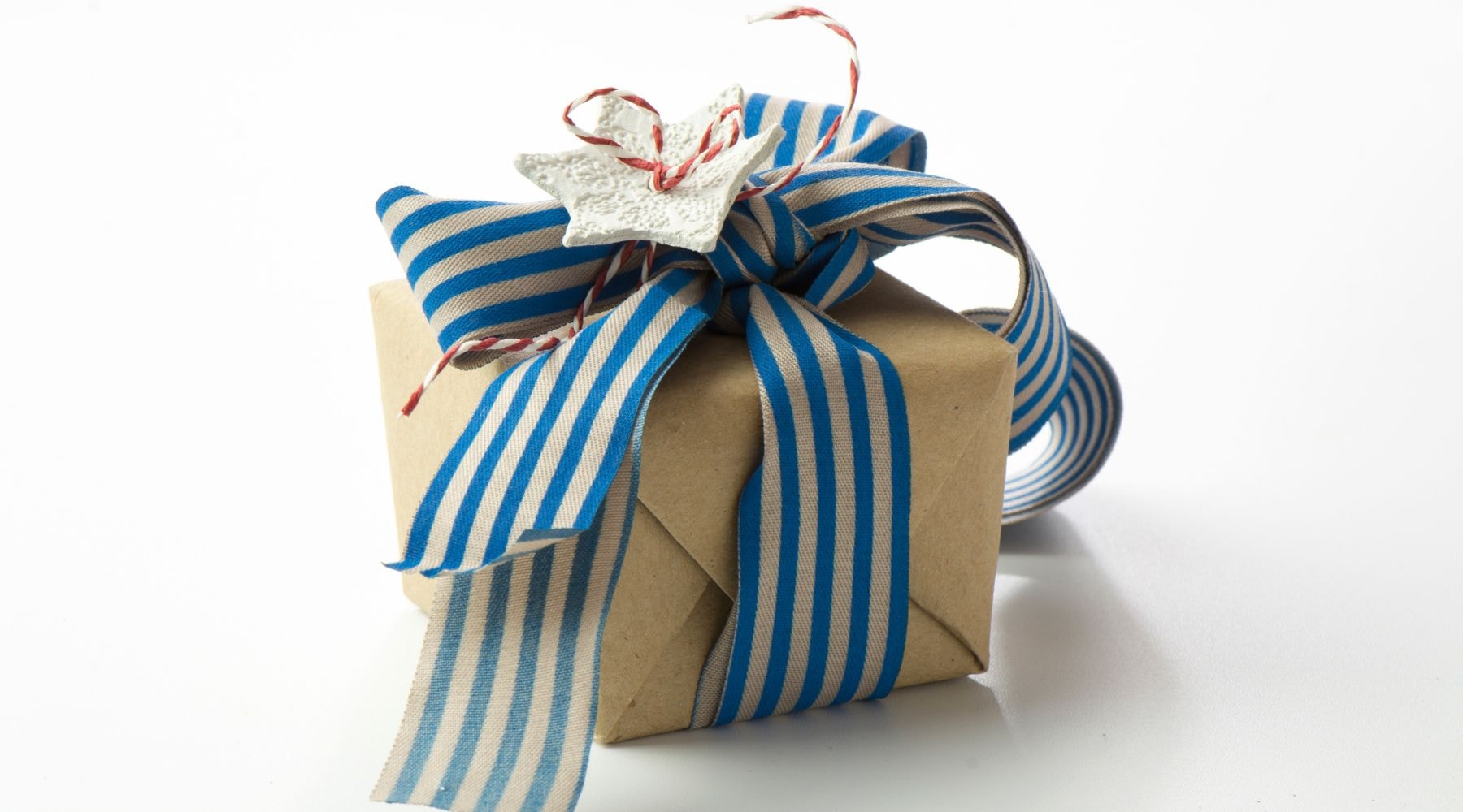 Craft paper gift wrapped with a blue striped ribbon and ceramic star decoration.