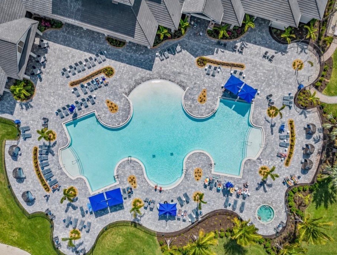 An aerial view of the WildBlue community showcases luxurious homes surrounding expansive freshwater lakes and preserved natural areas, highlighting the lakefront lifestyle and world-class amenities available to residents. The image captures the beauty of this master-planned community in Southwest Florida, with its private boat docks and lush landscapes ideal for an active lifestyle.