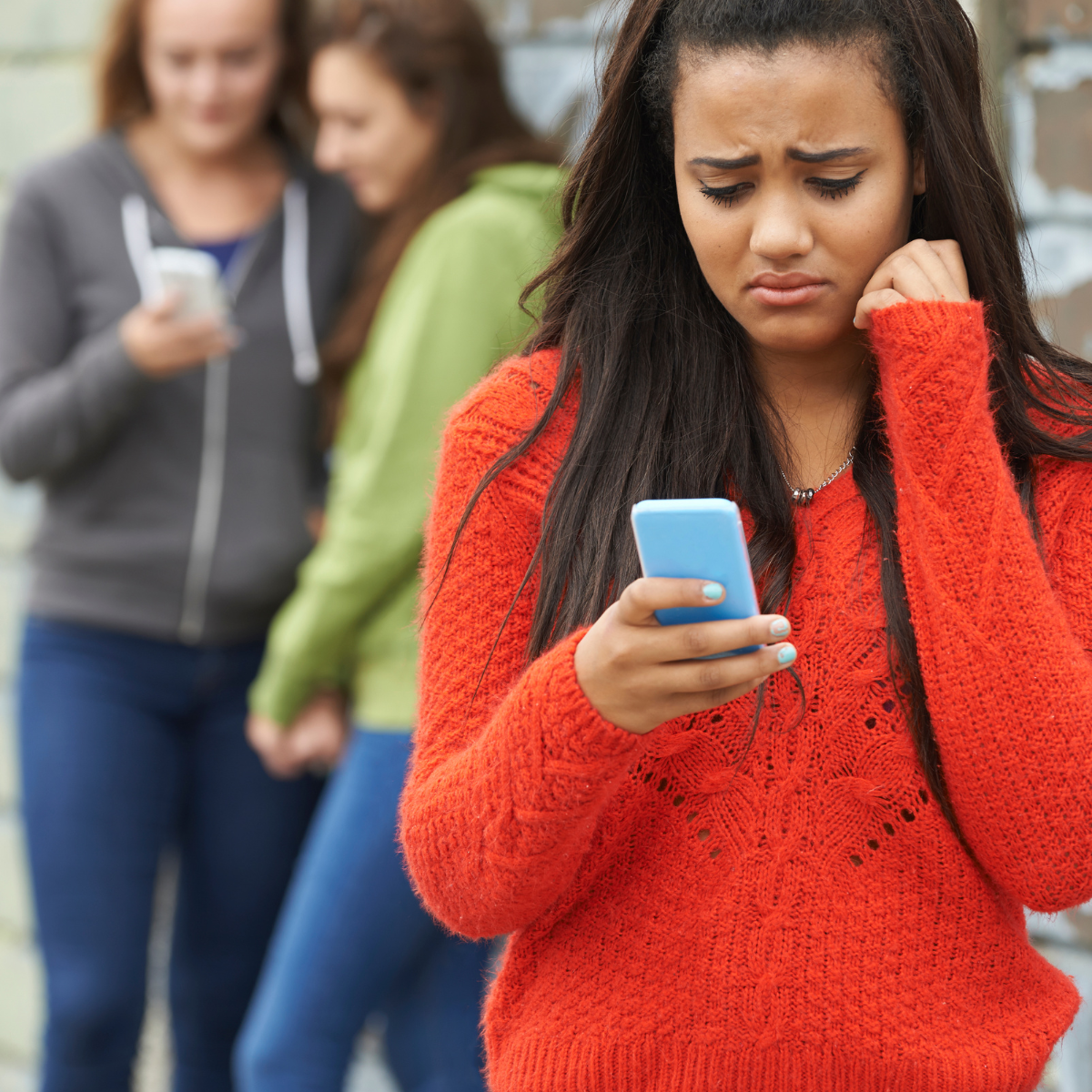 Girl checking phone with friends in background - Featured In : When An Ex Contacts You Years Later 