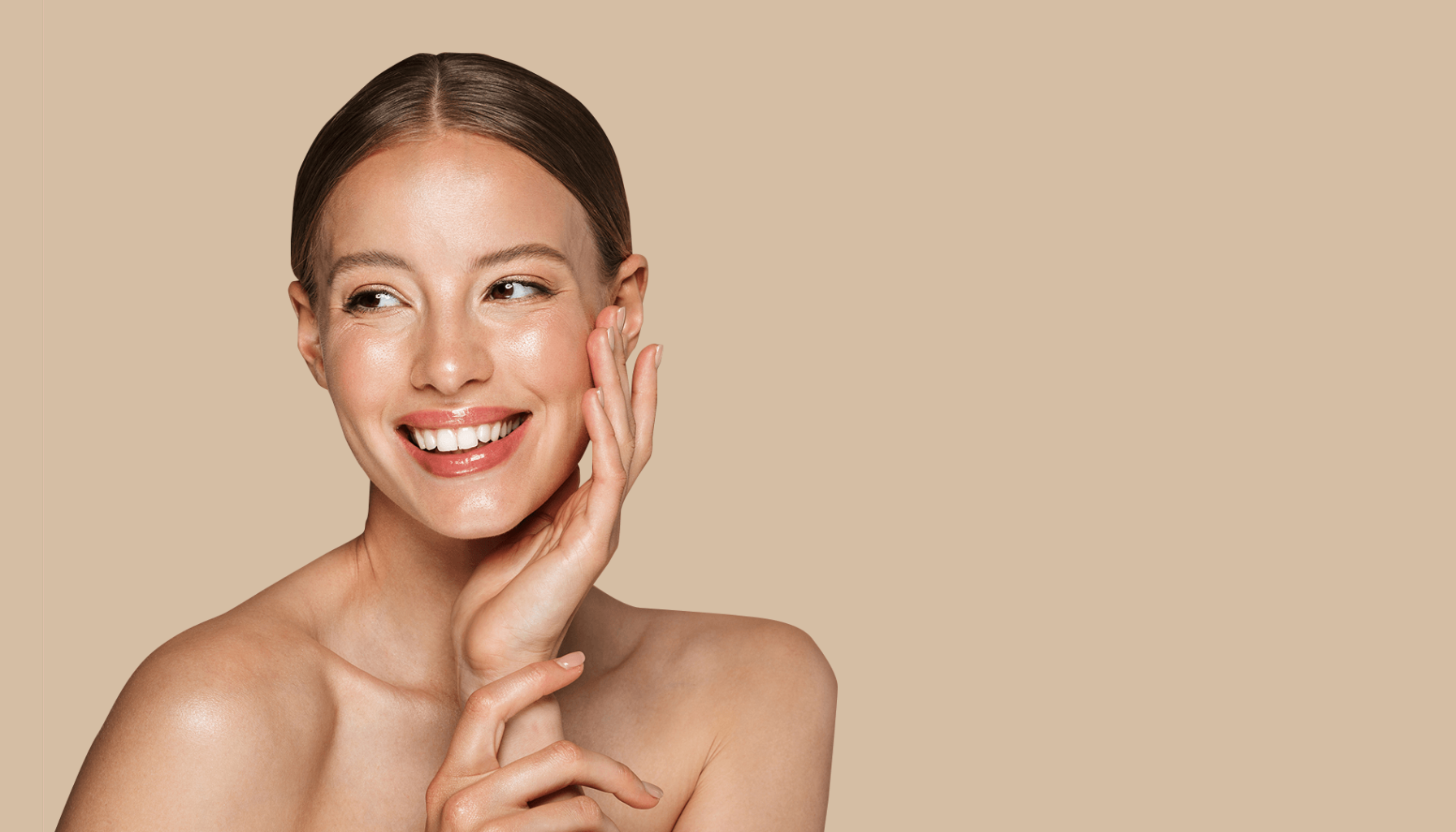 Kvinne med glødende hud smiler og berører ansiktet forsiktig.