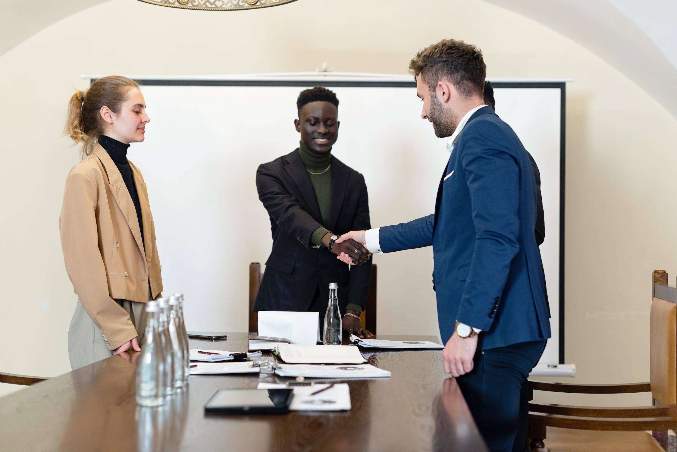 Man Shaking Hands With Another As Woman Looks On