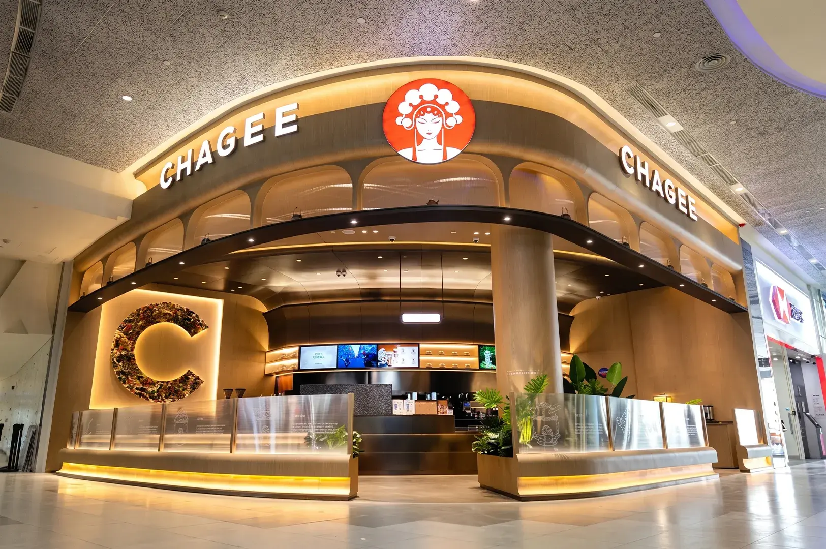 Wide storefront of a CHAGEE tea house featuring a curved wooden facade, illuminated signage, and a circular opera mask logo.
