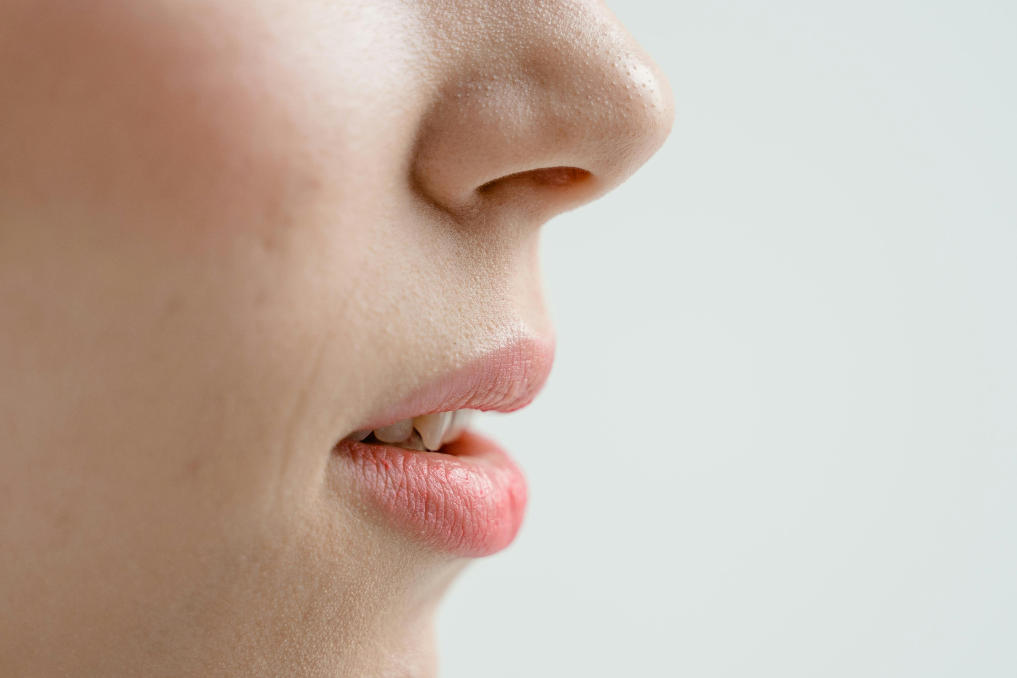 Close-up of a woman's mouth slightly open, displaying natural pink lips