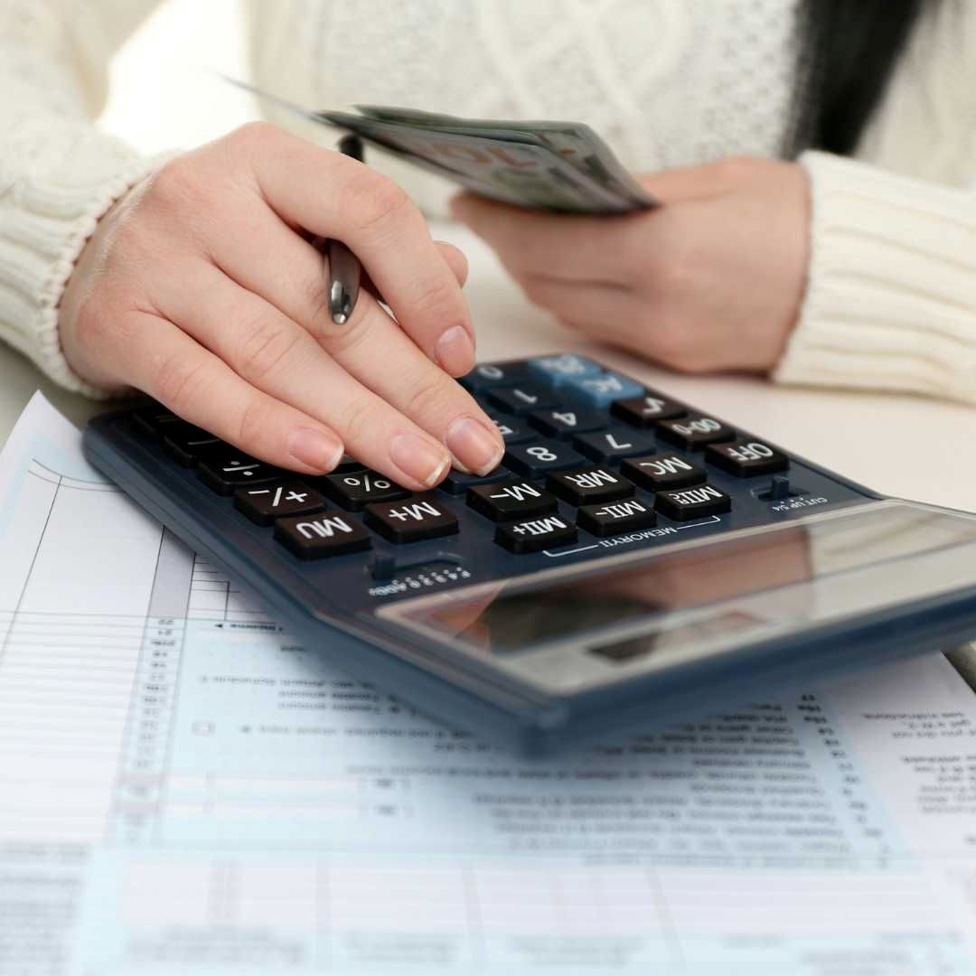 A person calculating their annual income on a calculator