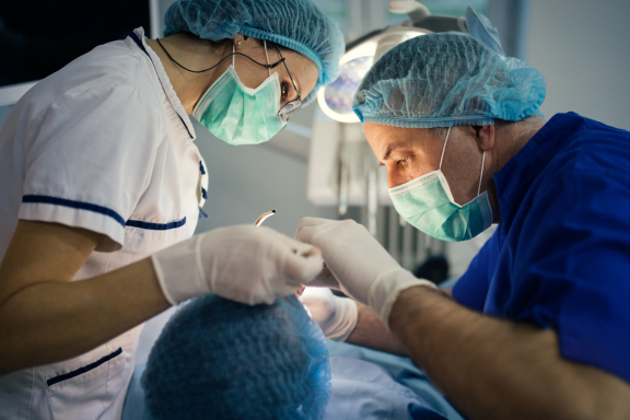 oral surgeon performs a single tooth implant on a patient in the operating table