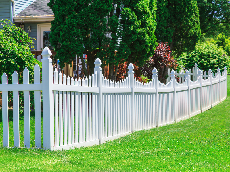 An image showing a durable vinyl fence with decorative vinyl posts in a sunny backyard.