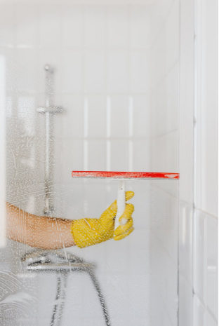 person cleaning glass shower wall