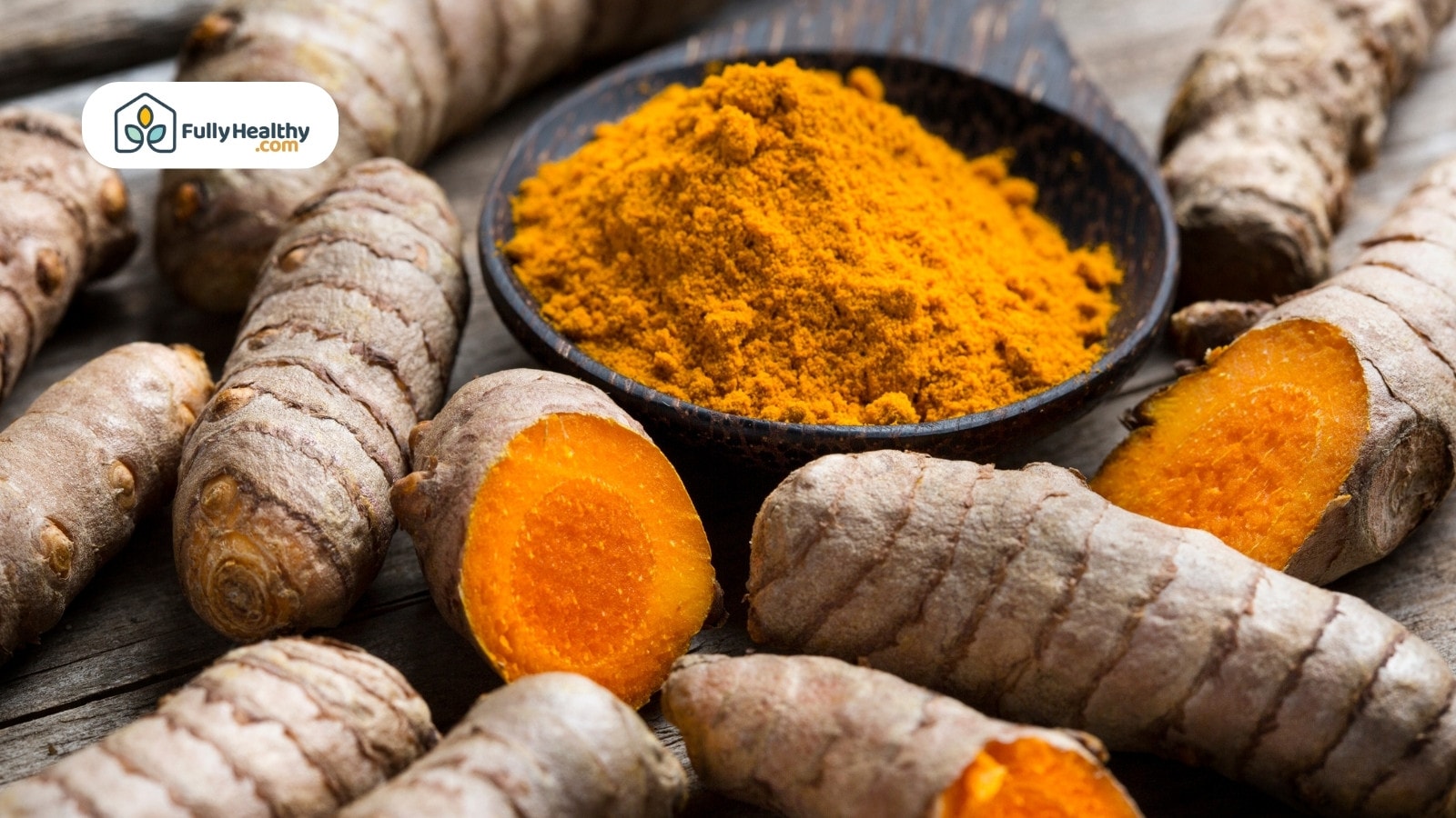 Bowl of turmeric powder surrounded by whole fresh turmeric roots