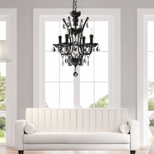 A black crystal chandelier hangs in a bright entryway above a white sofa, creating an elegant and sophisticated lighting focal point.