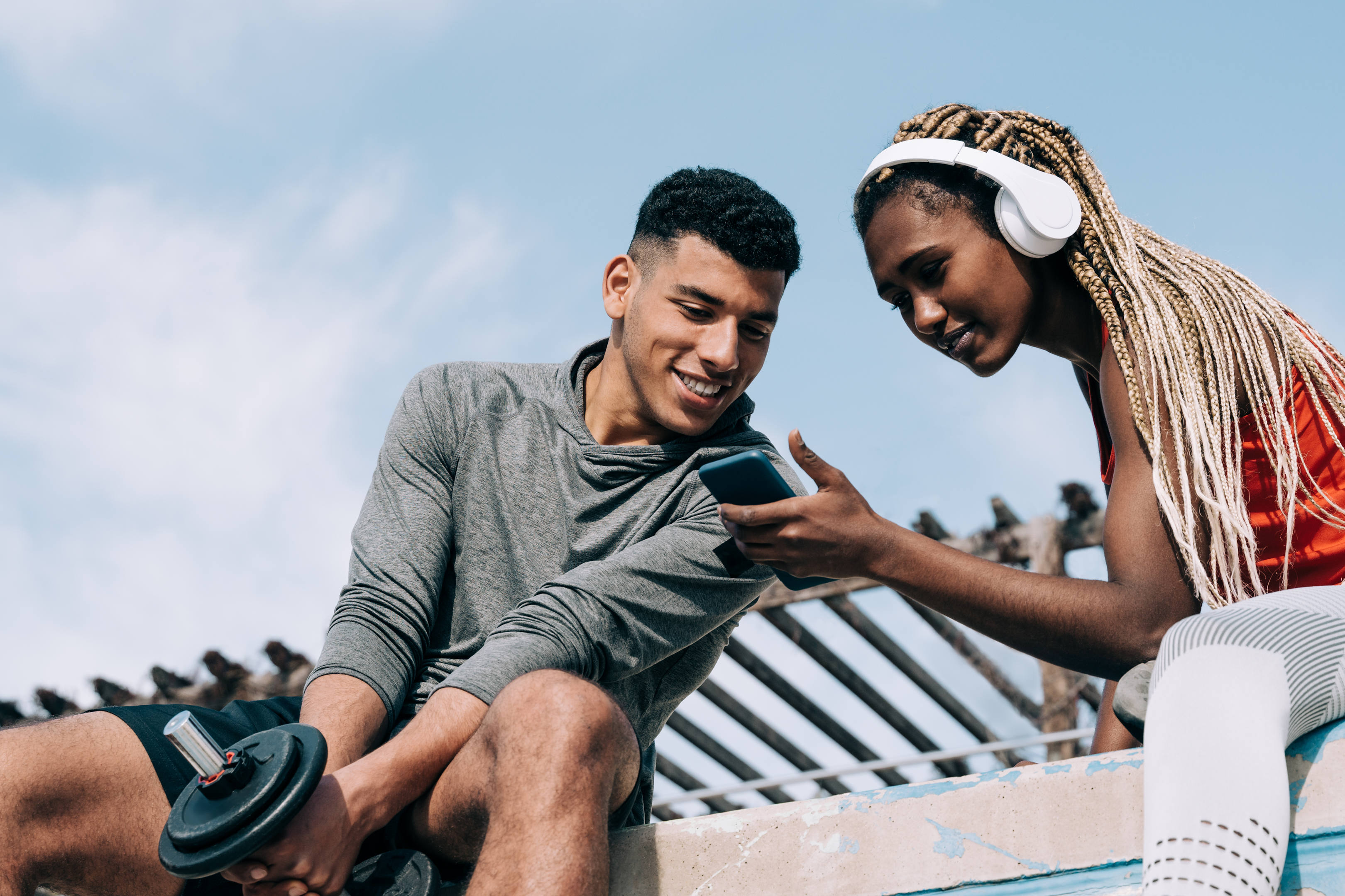 Two fit people looking at mobile while working out