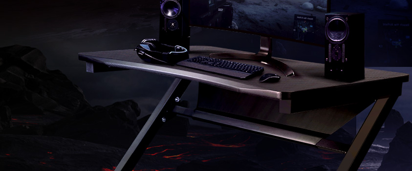 A black gaming desk, holding a gaming computer, speakers and headphones.