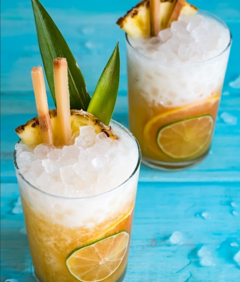 two glasses of pineapple juice with lots of ice and a garnish