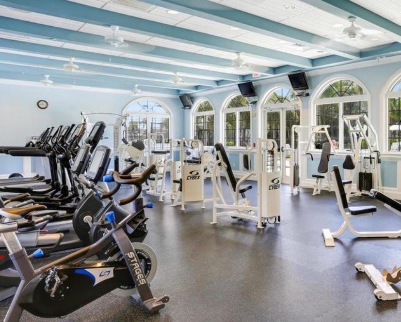 The image depicts a stunning resort-style clubhouse in North Fort Myers, featuring inviting swimming pools surrounded by lush palm trees and beautifully landscaped grounds, perfect for residents of Moody River Estates to enjoy. This vibrant community offers a variety of amenities, enhancing the lifestyle of those living in this gated community.