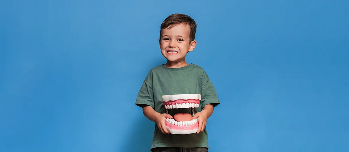 Child undergoes dental treatment with professional using instrument under light.