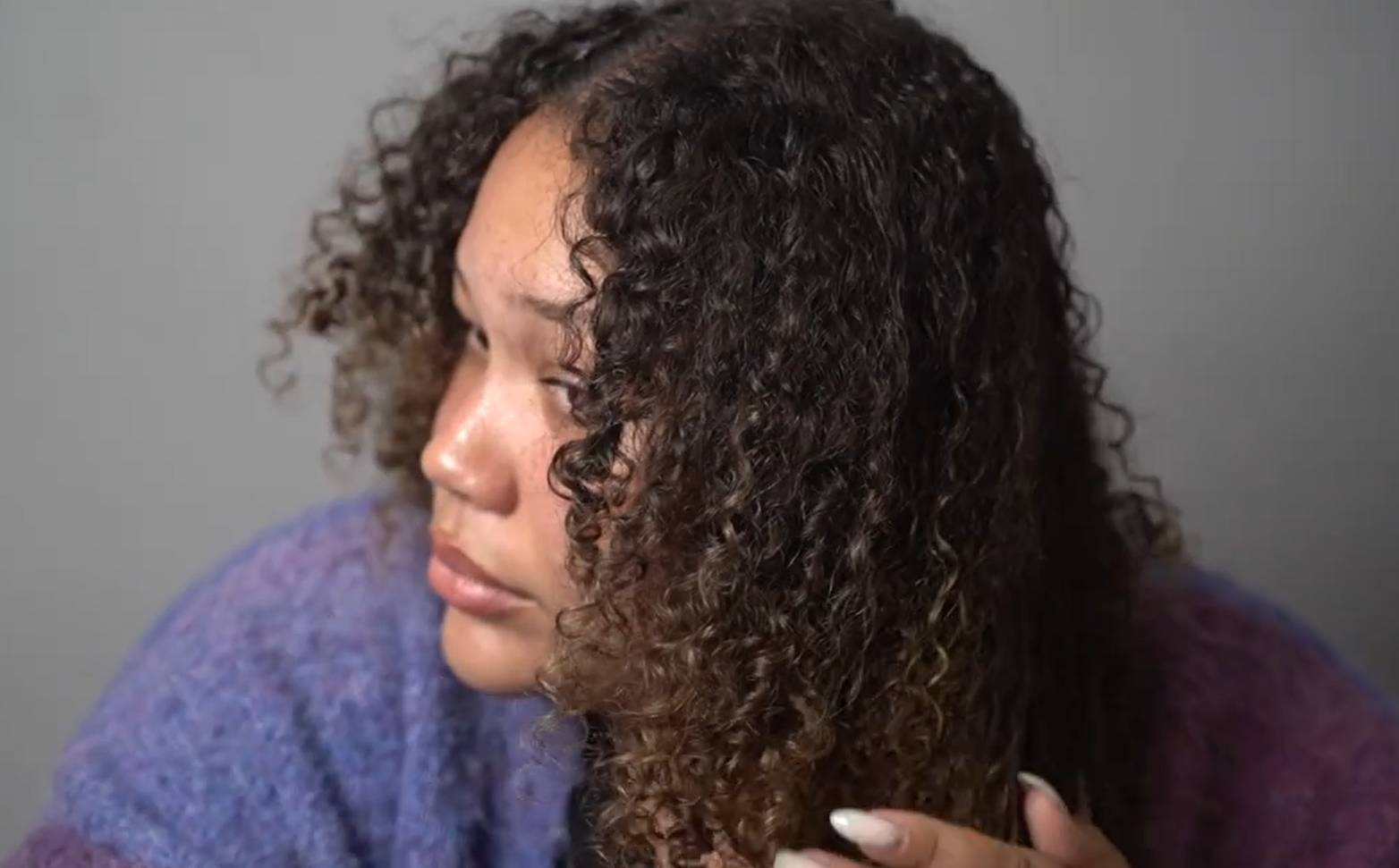 Tyler is rubbing the IGK Good Behavior Smoothing Spray to her curls