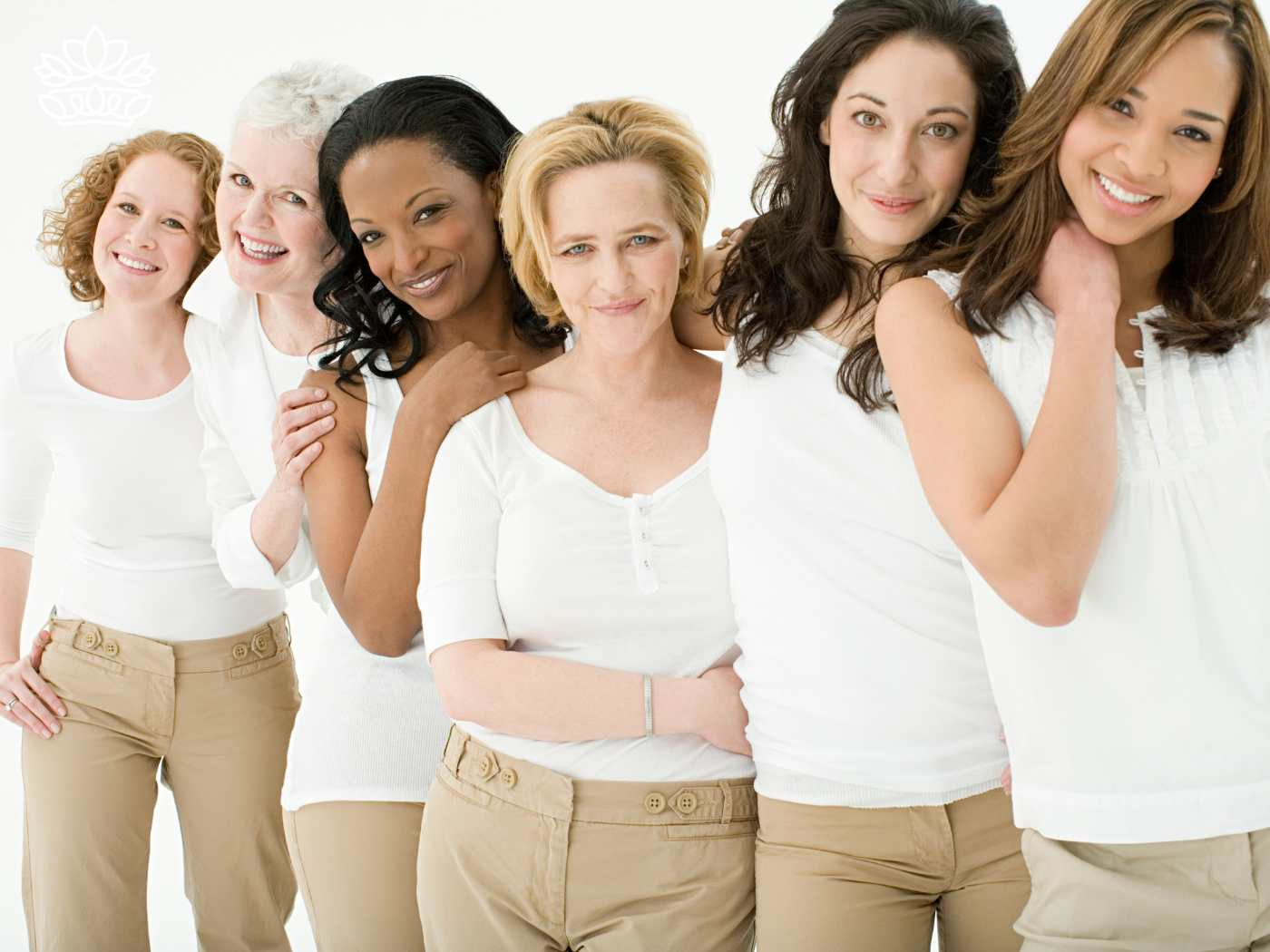 Group of five diverse women, friends of various ages, smiling and standing together in matching white tops and beige trousers. Ideal for moms and friends searching for the perfect anniversary gift, capturing the essence of mattering in every shopping choice from the Gifts Boxes for Women Collection. Fabulous Flowers and Gifts.