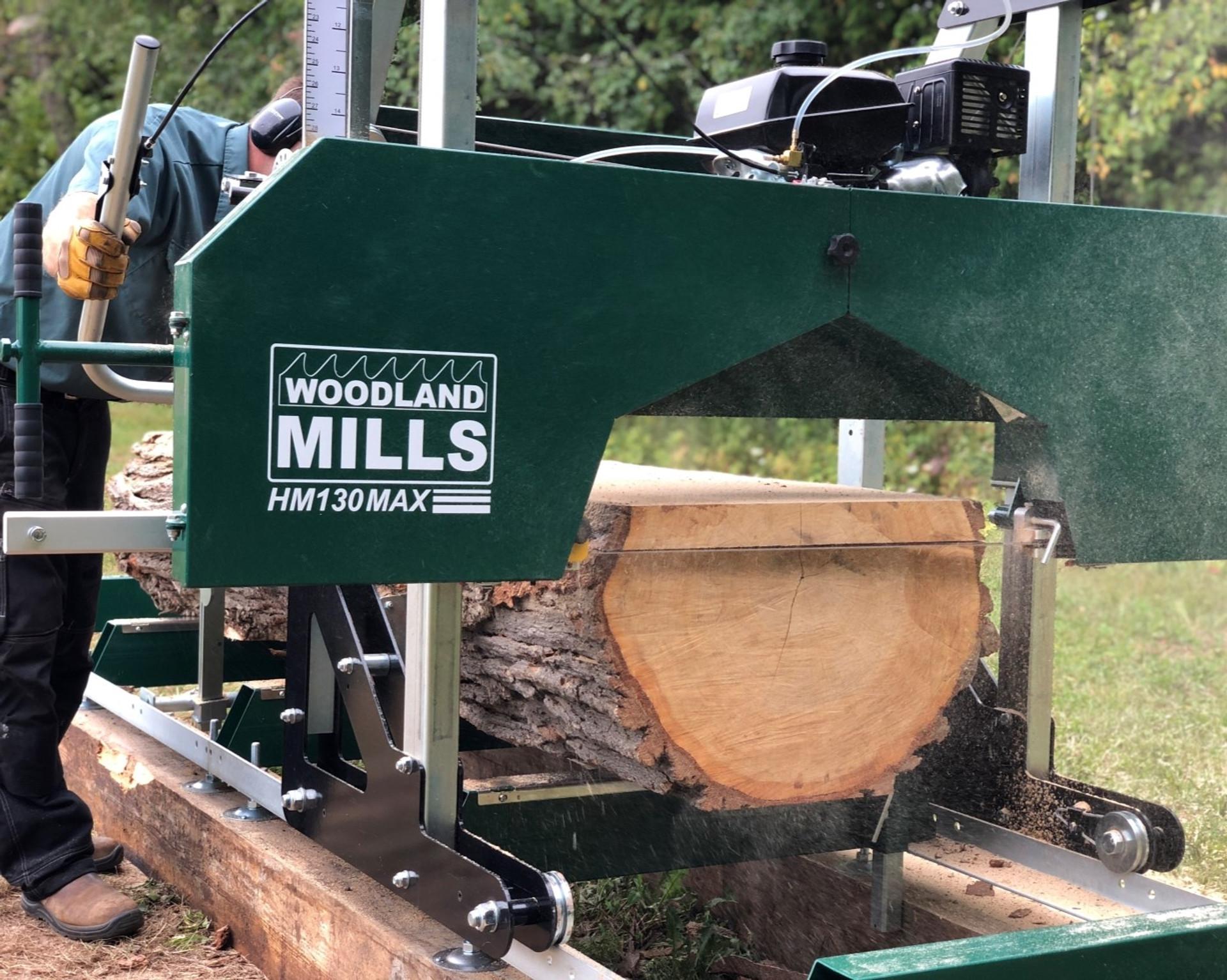 A landowner pushing a Woodland Mills HM130MAX Portable Sawmill through a log. 