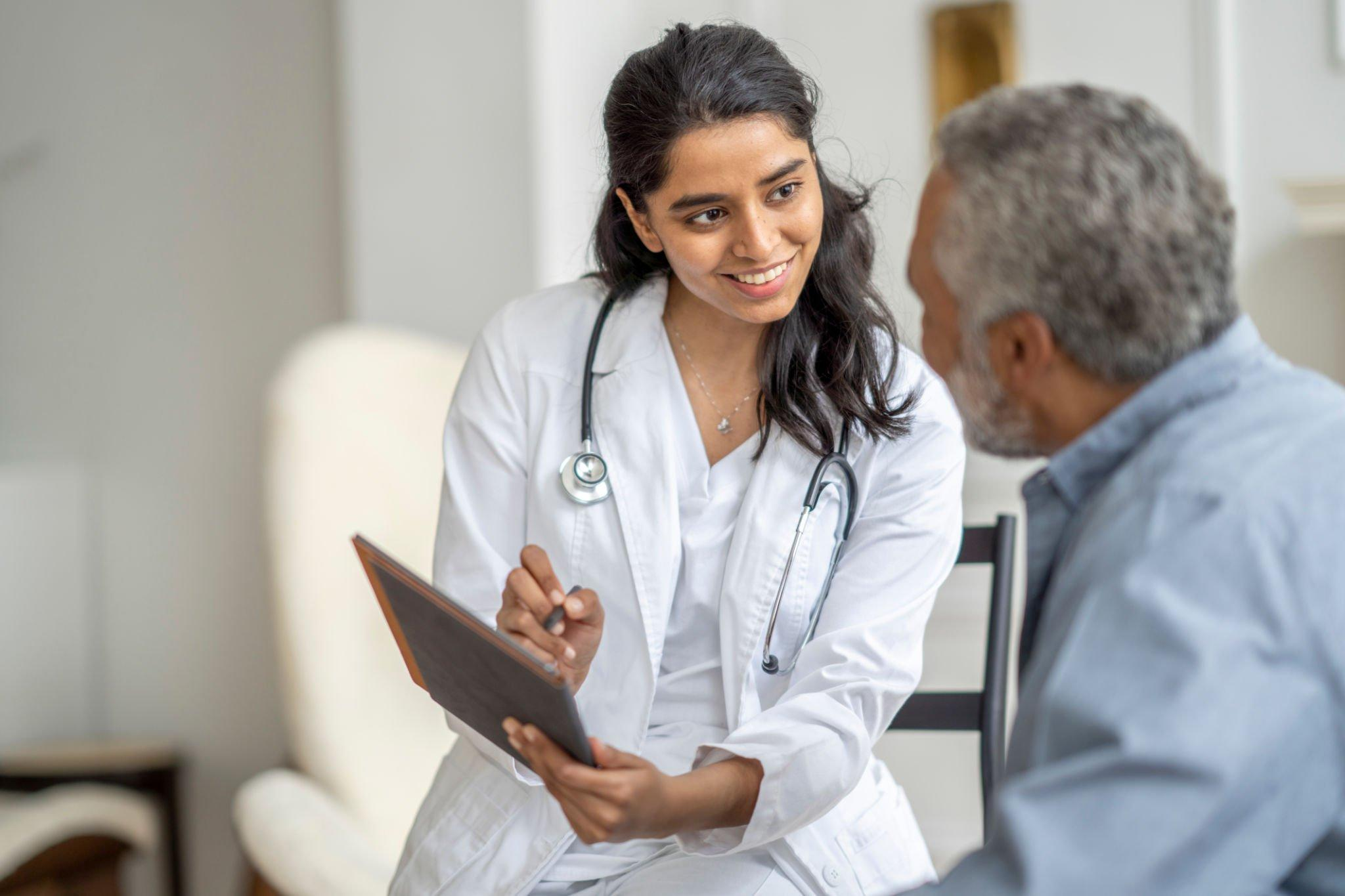 A doctor discussing a document with a patient, addressing Medicare coverage related to diabetes and the benefits of using a CGM system
