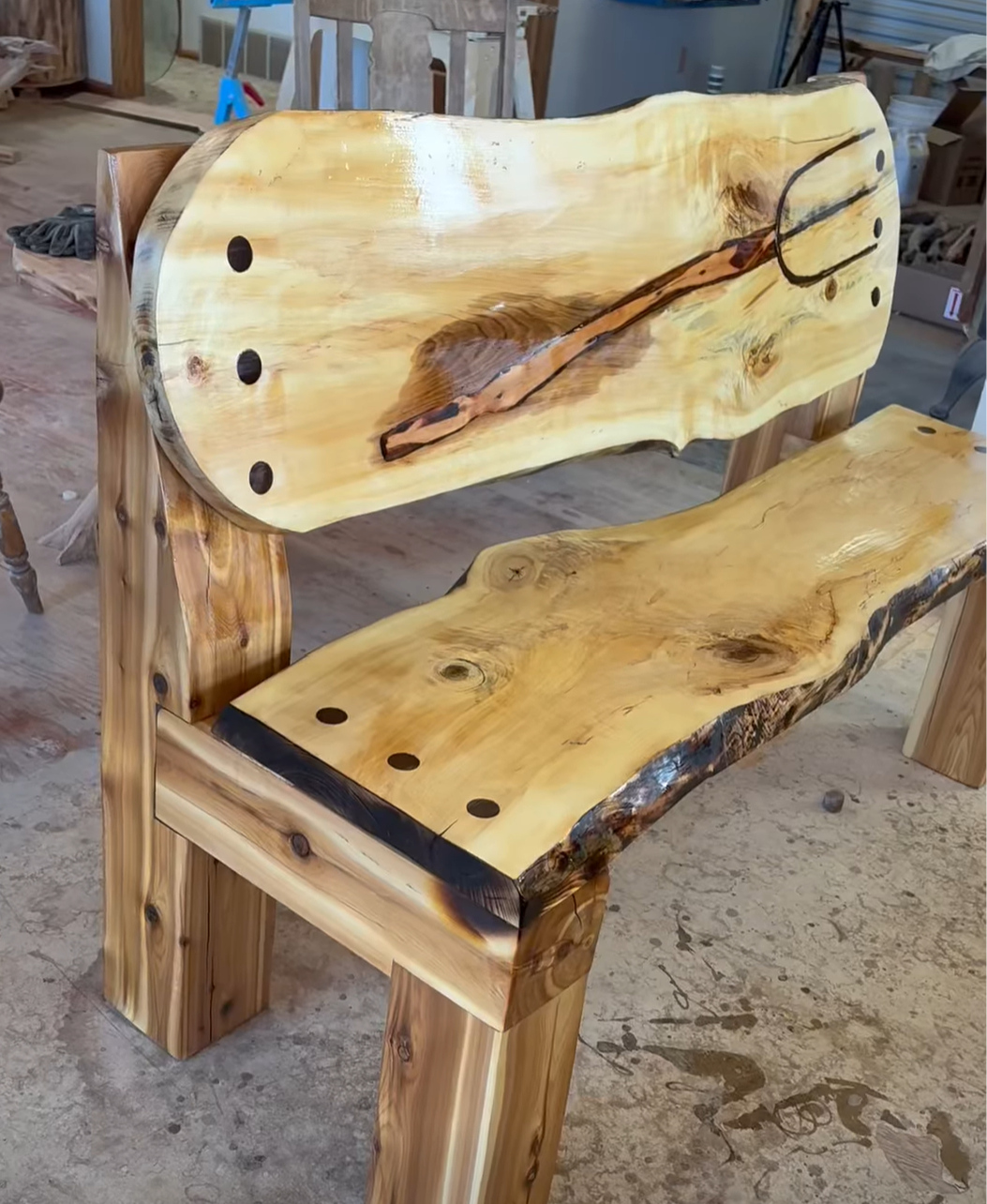 A live edge slab bench made with a portable sawmill and a design of a pitch fork on the back.