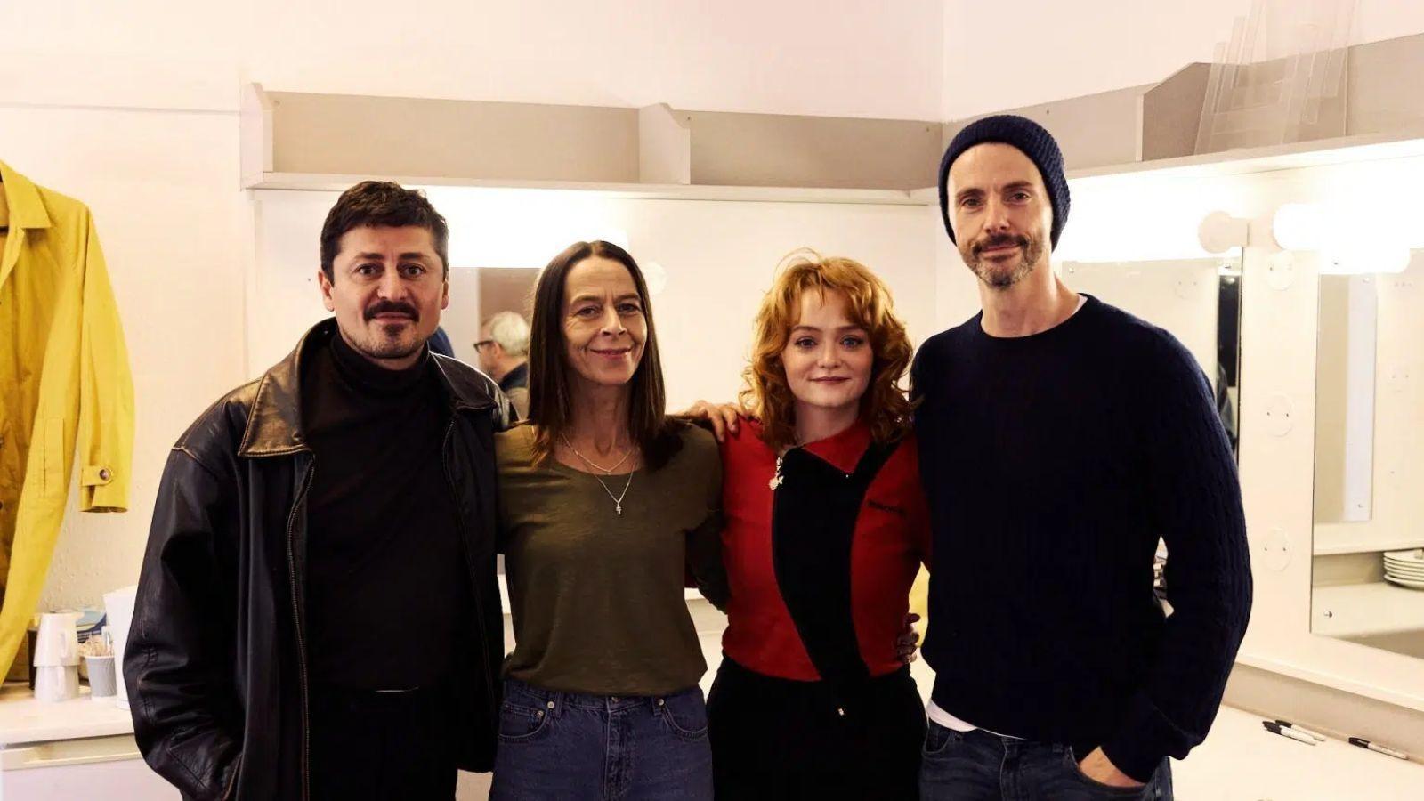 Dept. Q cast members posing together backstage in a dressing room