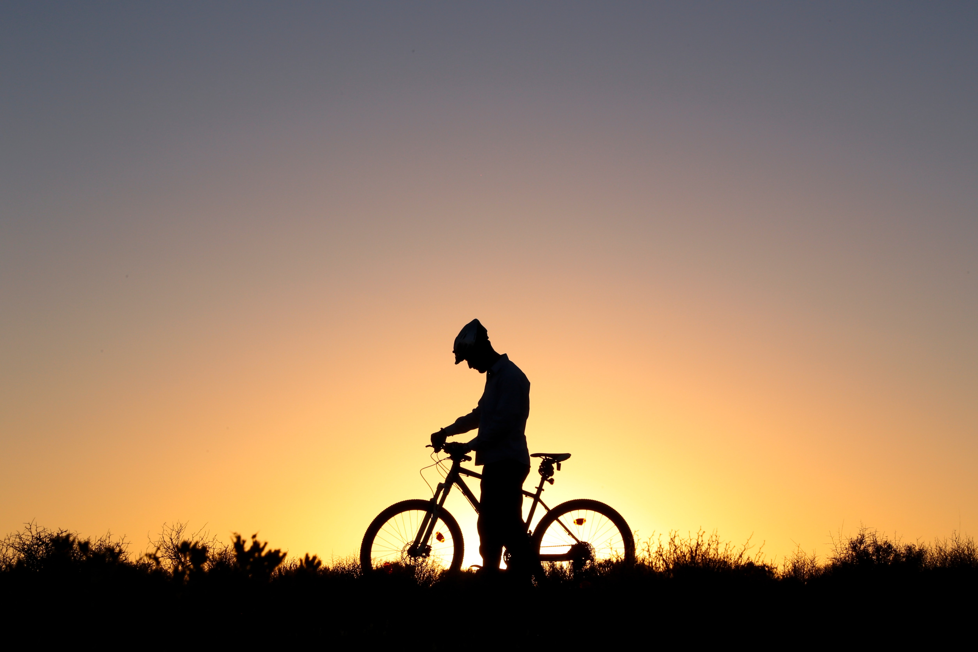 Ciclista no por do sol com sua bike. Foto: Unsplash