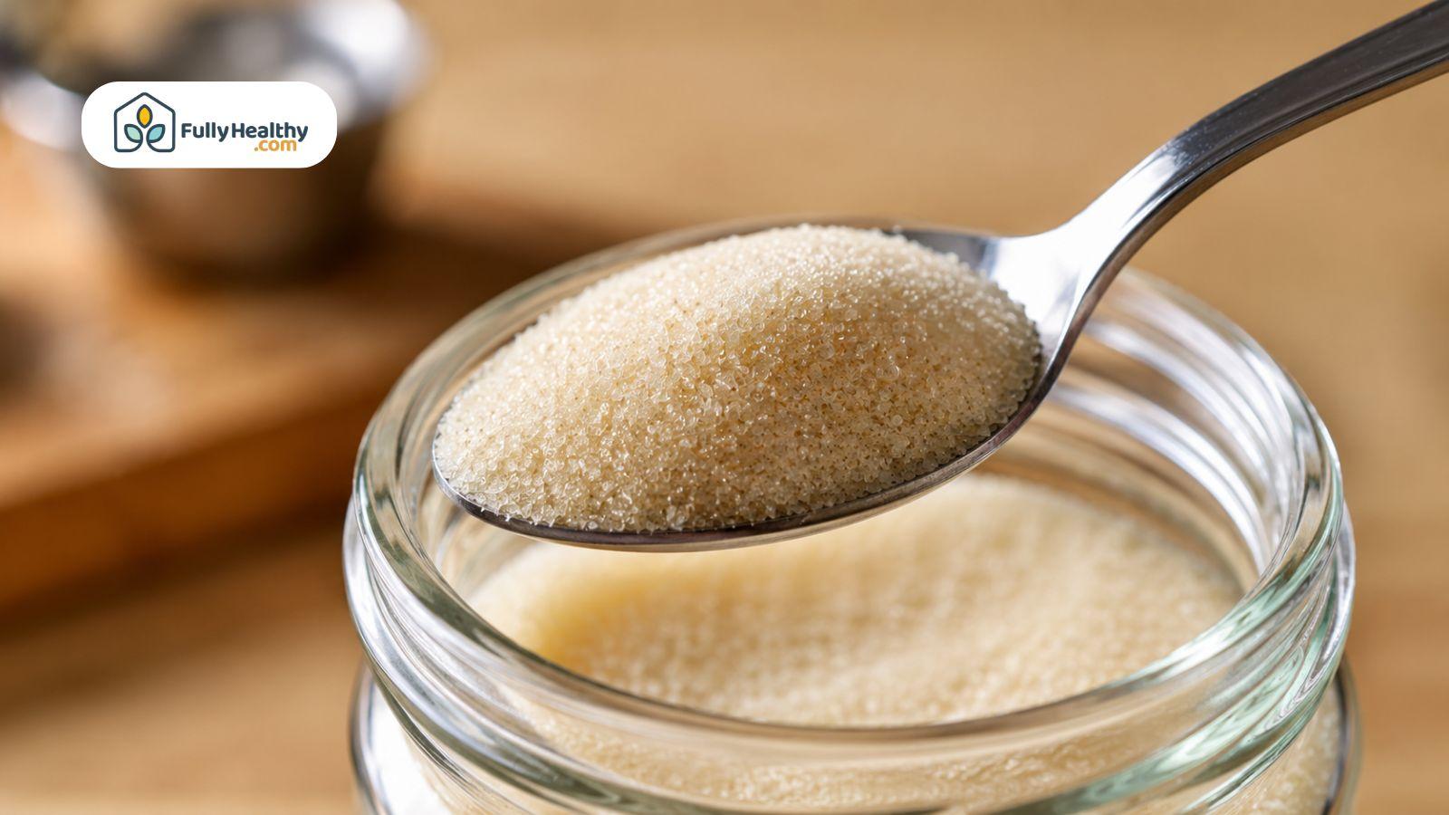 Close-up of unflavored gelatin powder on a spoon above a glass jar.