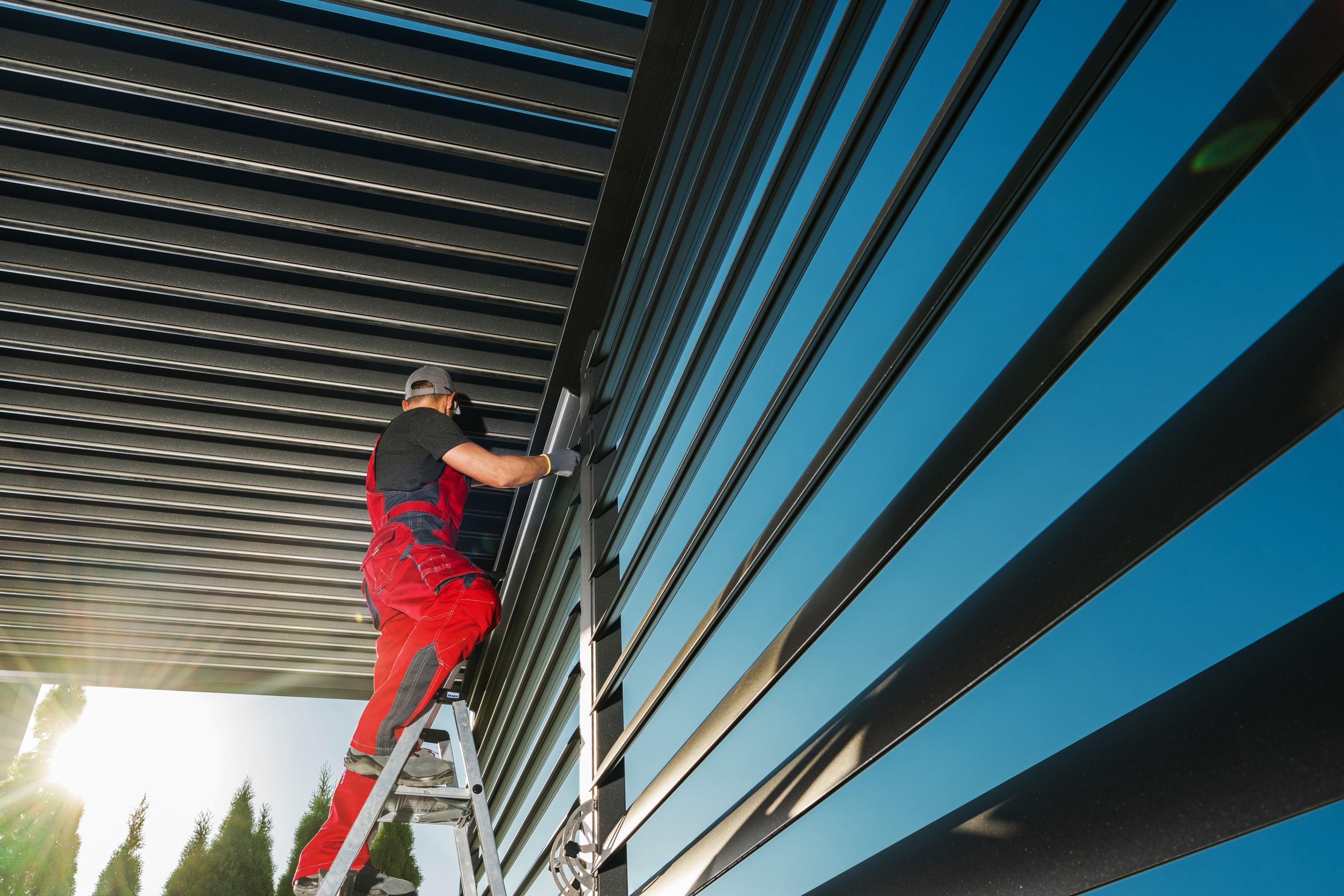 Pergola installer building an aluminum louvered pergola with a slat wall.