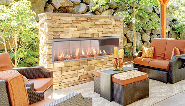 Outdoor fireplace in a backyard with a stone wall and a wooden bench