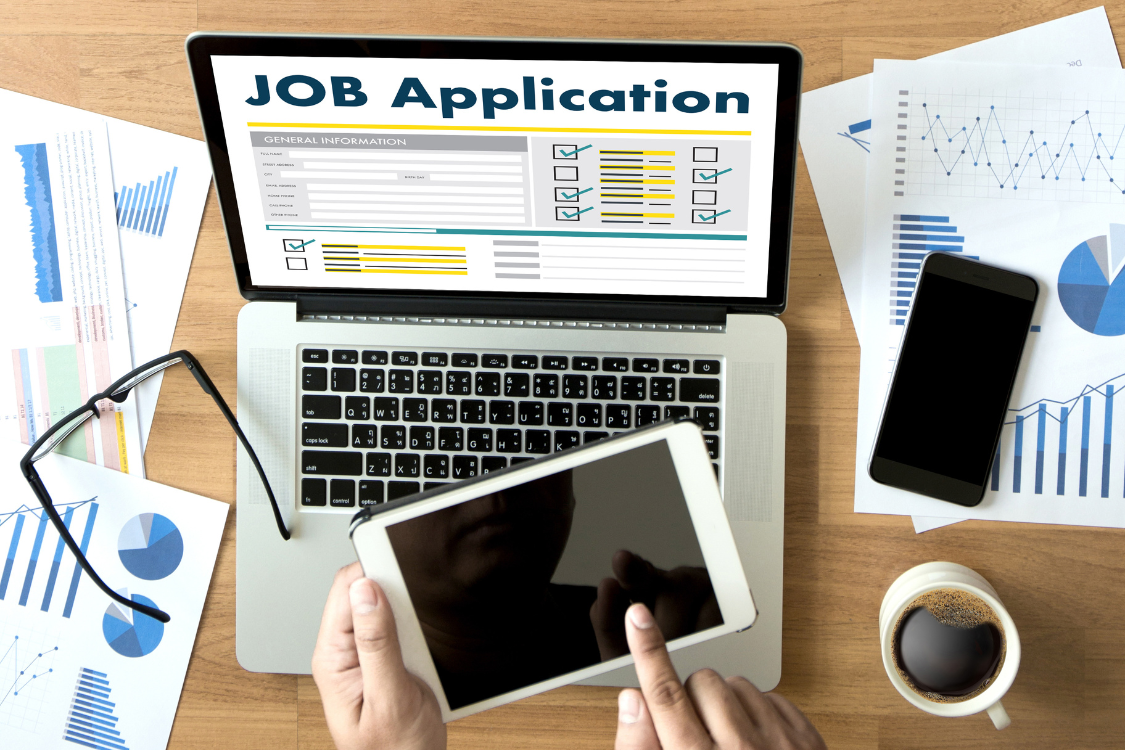 Laptop screen showing job application form with tablet and documents on the desk