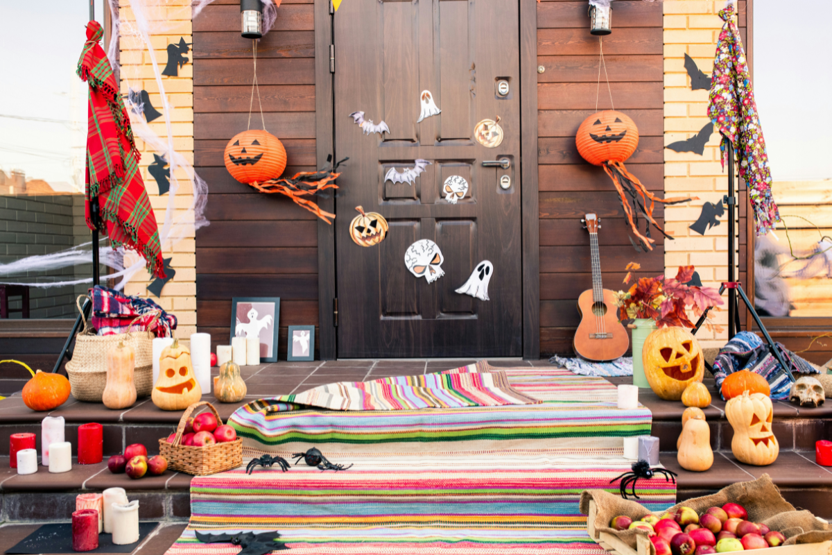 A stylish yet spooky Halloween porch decorated with pumpkins and eerie lights.