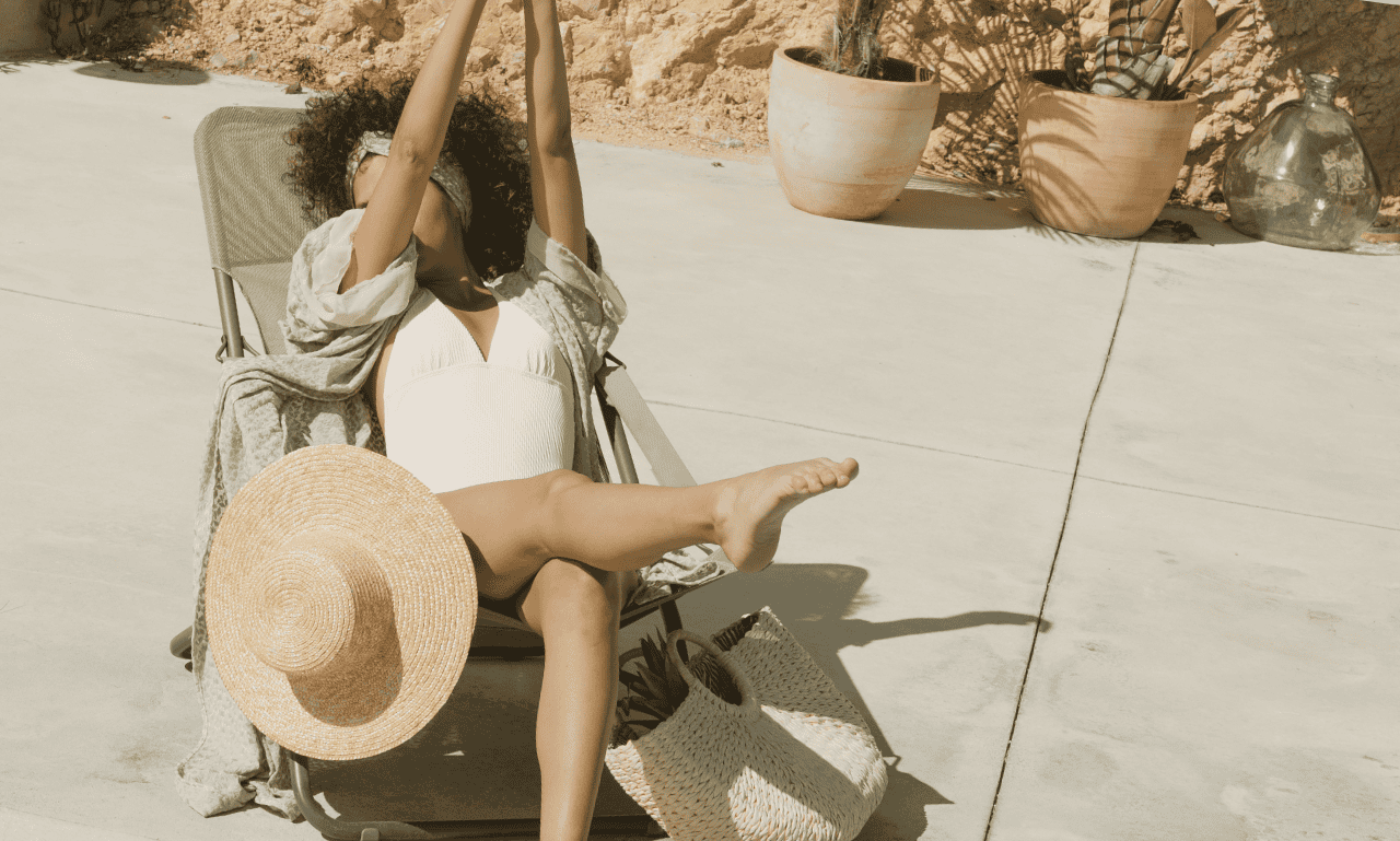 A woman sitting with her bag and hat hanging out by the pool!